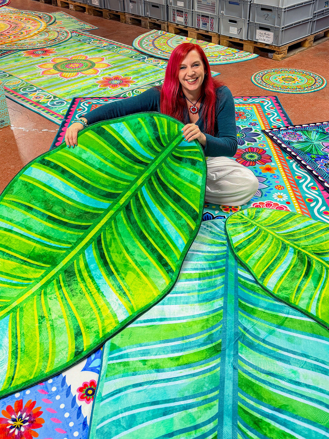 Superweicher Teppich im Design von Bine Brändle in Form eines Bananenblatts mit Motiv in Türkis und Grün, tropisch und modern gestaltet.
